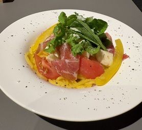 生ハムとトマトの冷製パスタ・ルッコラ添え〈米粉入カボチャ麺〉